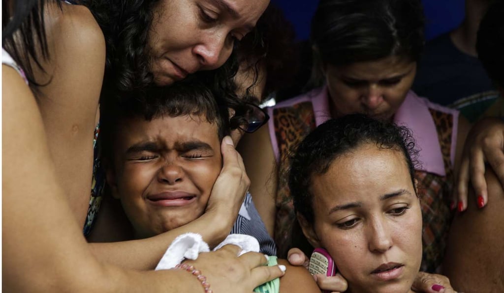 Kailua, centre, son of slain civil police officer Mario Marcelo de Albuquerque Espirito, is comforted during his father's funeral on Wednesday, alongside his mother Patricia Albuquerque, right, in Serra in Brazil’s Espirito Santo state. Espirito was shot to death when he tried to stop a robbery. Photo: AP