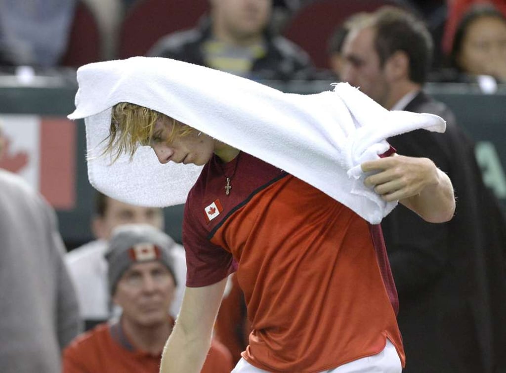 Canada's Denis Shapovalov covers his head with a towel as he leaves after his match was declared forfeited by umpire Arnaud Gabas, of France, when he was hit in the face with a ball. Photo: AP