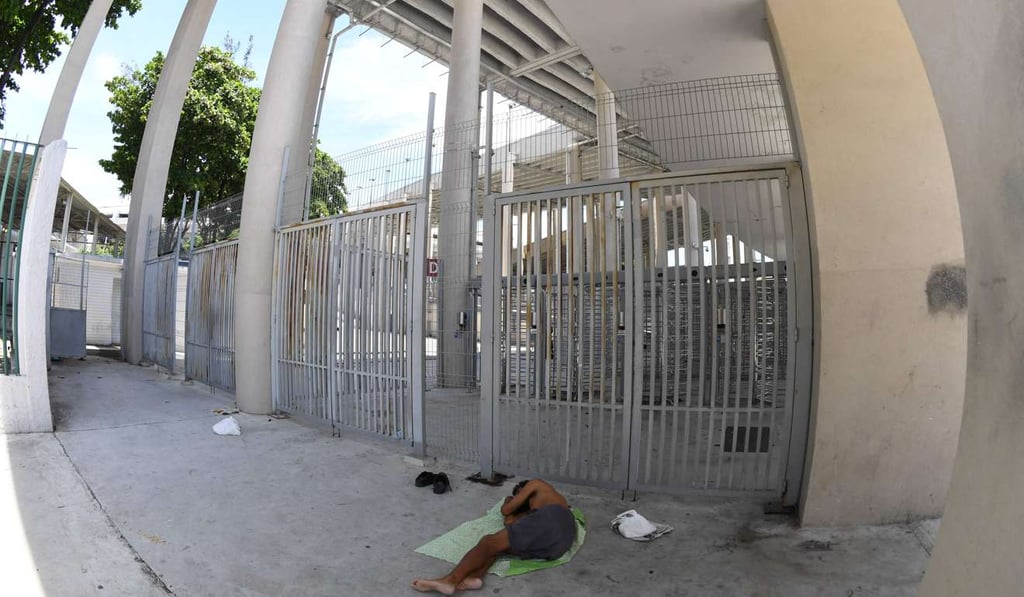 A homeless man sleeps outside the closed main gates to the Maracana Stadium in Rio de Janeiro. Photo: AFP