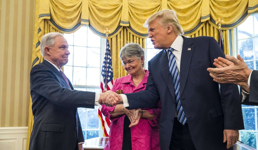 US President Donald Trump (right) shakes hands with Attorney General Jeff Sessions (left) while Sessions' wife, Mary Blackshear Sessions looks on shortly after Sessions was sworn-in by Vice-President Mike Pence in the Oval Office of the White House on February 9. Photo: EPA