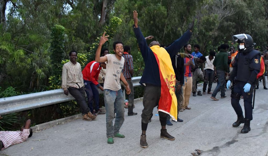 Migrants celebrate outside the Center for Temporary Stay of Immigrants (CETI) after forcing their way through a border fence. Photo: AFP Migrants celebrate outside the Center for Temporary Stay of Immigrants (CETI) after forcing their way through a border fence. Photo: AFP