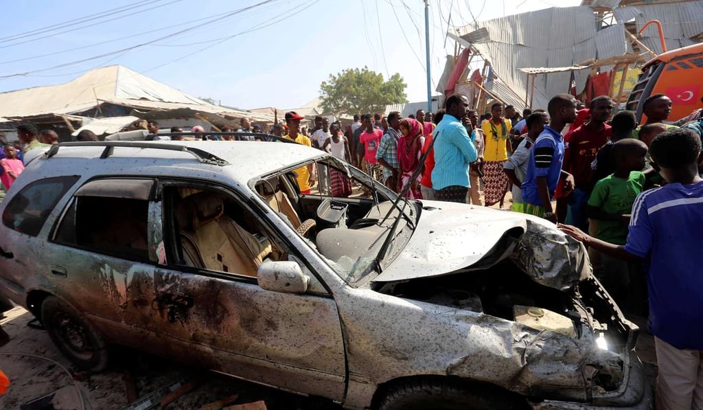 Civilians stand near a car destroyed in a suicide bomb explosion at the Wadajir market in Madina district of Somalia's capital Mogadishu, on Sunday. Photo: Reuters