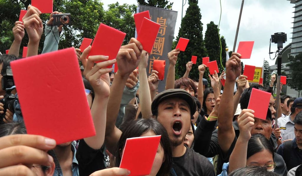 Anti-mainland demonstrators hold up red cards in June 2014 outside a hotel where Zhang Zhijun, Beijiing’s top official for Taiwan official, was staying on his first visit to the island. Photo: AFP