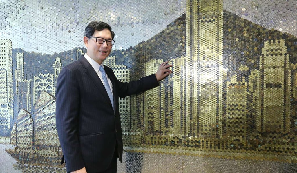Norman Chan stands in front of the artwork showing a picture of the skyline of Victoria Harbour created from 135,811 coins. Photo: Dickson Lee