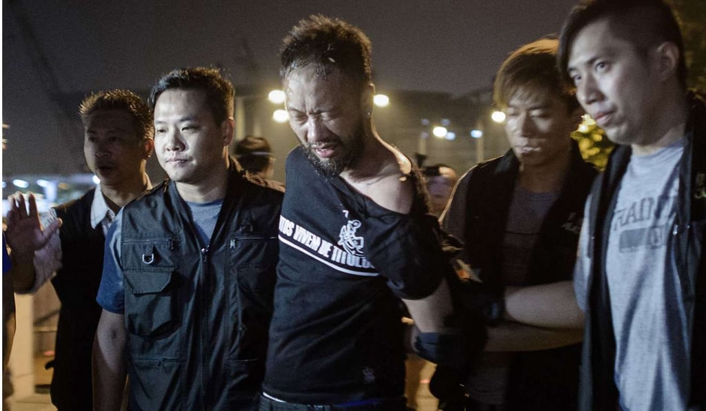 Ken Tsang (centre) is taken away by police officers on October 15, 2014, outside the government headquarters in Hong Kong. Photo: AFP