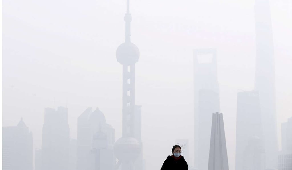 A woman wearing a face mask stands on a bridge in front of the financial district of Pudong amid heavy smog in Shanghai in 2015. Photo: Reuters