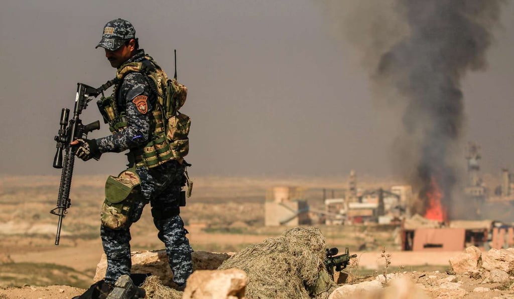 Smoke rises from a burning factory as an Iraqi security forces sniper takes a position near Mosul’s airport on Thursday. Photo: Reuters