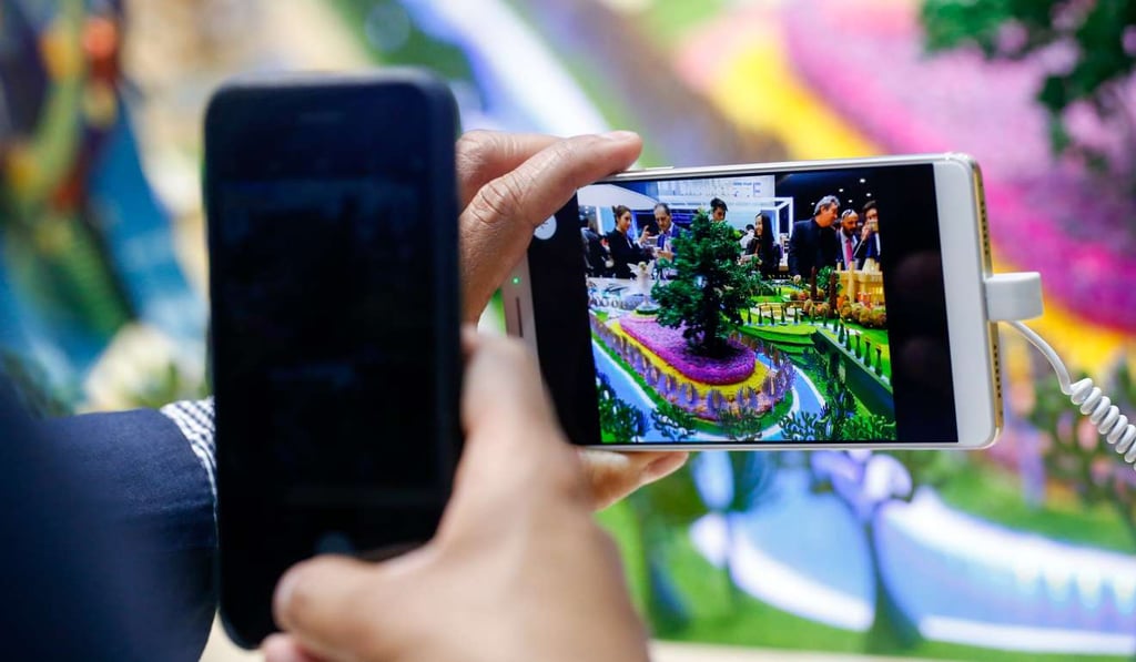 An attendee uses a smartphone to take a photograph of a Axon 7 smartphone, manufactured by ZTE Corp., on the opening day of the Mobile World Congress in Barcelona, Spain, on February 27, 2017. Photo: Bloomberg
