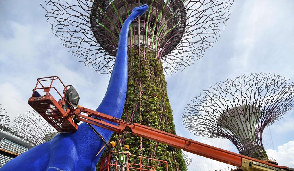 Workers stitch the neck of an animated dinosaur displayed under the “Supertrees” at Gardens by the Bay in Singapore. Eleven multicoloured, life-sized replicas of dinosaurs will be on display in March to celebrate a children’s festival. Living standards in Singapore are now about 35 per cent higher than those in America. Photo: AFP Workers stitch the neck of an animated dinosaur displayed under the “Supertrees” at Gardens by the Bay in Singapore. Eleven multicoloured, life-sized replicas of dinosaurs will be on display in March to celebrate a children’s festival. Living standards in Singapore are now about 35 per cent higher than those in America. Photo: AFP