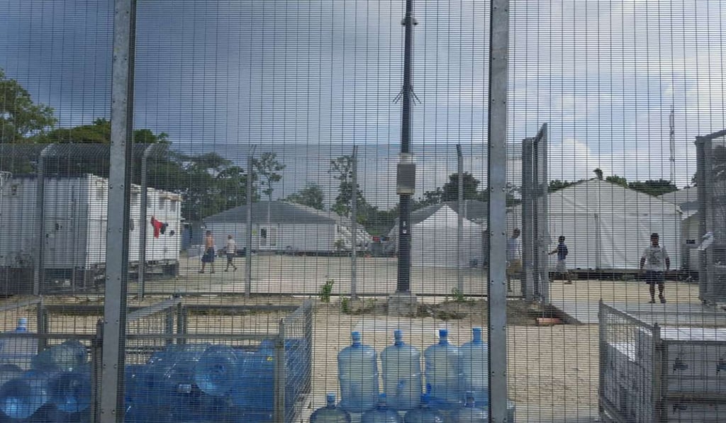 Detainees walk around the compound near a stack of water bottles inside the Manus Island detention centre in Papua New Guinea. Photo: Reuters