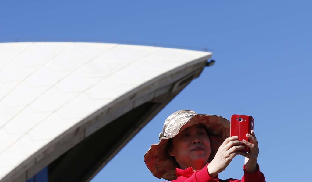 A Chinese tourist takes a picture from the steps of the Sydney Opera House in central Sydney. Photo: Reuters
