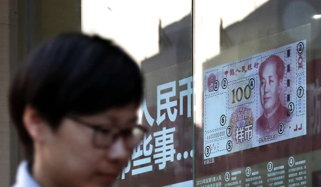 A pedestrian passes by a bank window panel displaying the security markers on the renminbi banknote in Beijing. Photo: AP