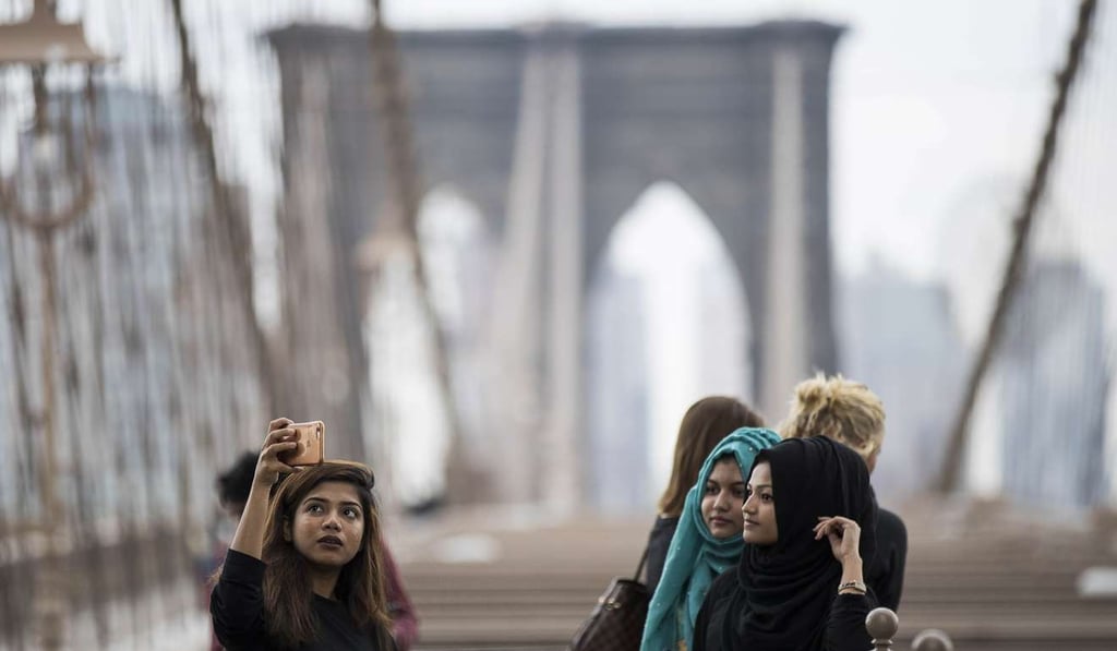 Tourists take photographs on the Brooklyn Bridge in New York City. Photo: AFP Tourists take photographs on the Brooklyn Bridge in New York City. Photo: AFP