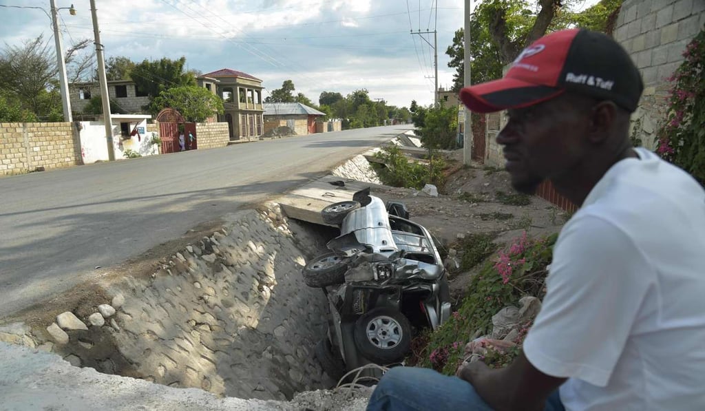 A smashed car lies in a ditch after apparently having been run off the road by a speeding bus that ploughed through a crowd in northern Haiti. Photo: AFP