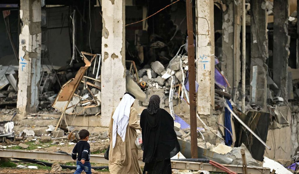 A displaced Iraqi family who fled from clashes during a battle between Iraqi forces and Islamic State militants, walk near destroyed buildings, in the city of Mosul, Iraq. Photo: Reuters