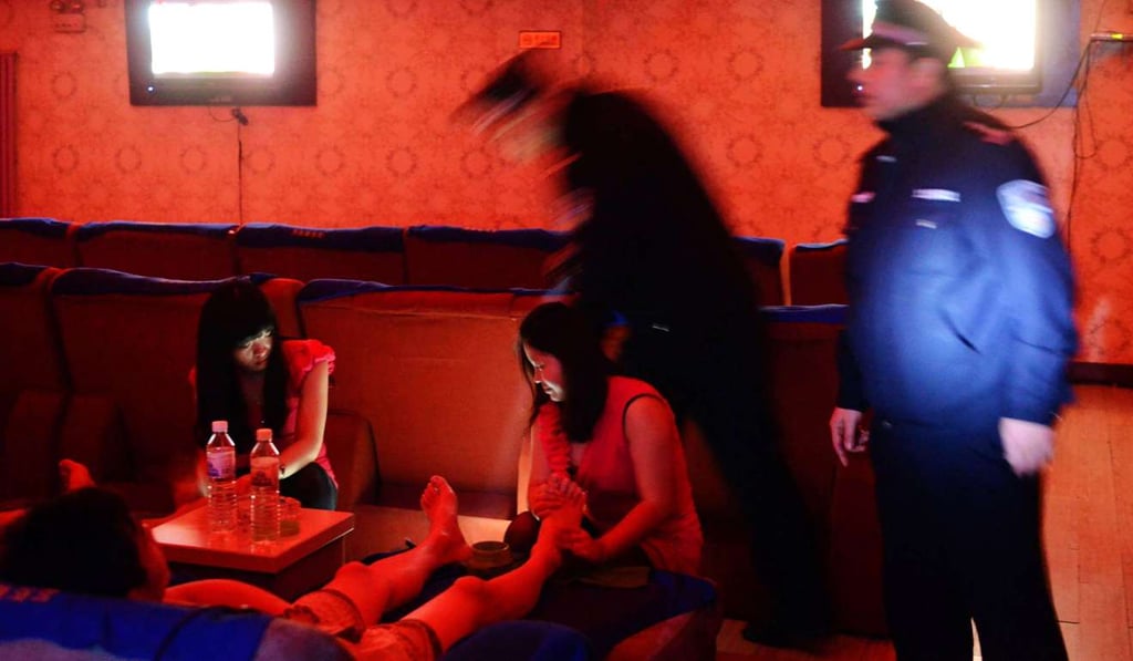 Policemen check a public bath house as masseurs serve their guests in Qingdao, east China’s Shandong province. Photo: AFP Policemen check a public bath house as masseurs serve their guests in Qingdao, east China’s Shandong province. Photo: AFP