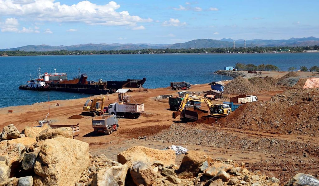 Trucks and a back hoe load rocks and soil containing nickel-ore minerals into a barge in the mining town of Sta Cruz Zambales in the northern Philippines. Photo: Reuters