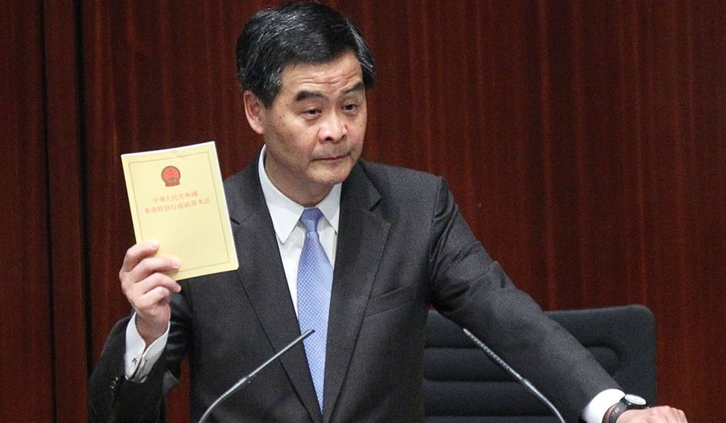 Chief Executive Leung Chun-ying, who is due to step down this year, holds up a copy of the Basic Law during a Legislative Council meeting in 2013. It is imperative that any discussion on the future of “one country, two systems” begins with the Basic Law. Photo: K. Y. Cheng