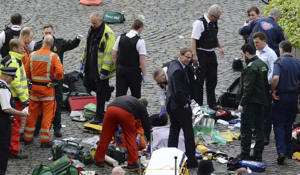 Conservative MP Tobias Ellwood (centre, in suit) stands among the emergency workers at the scene outside the Palace of Westminster in London. Photo: AP