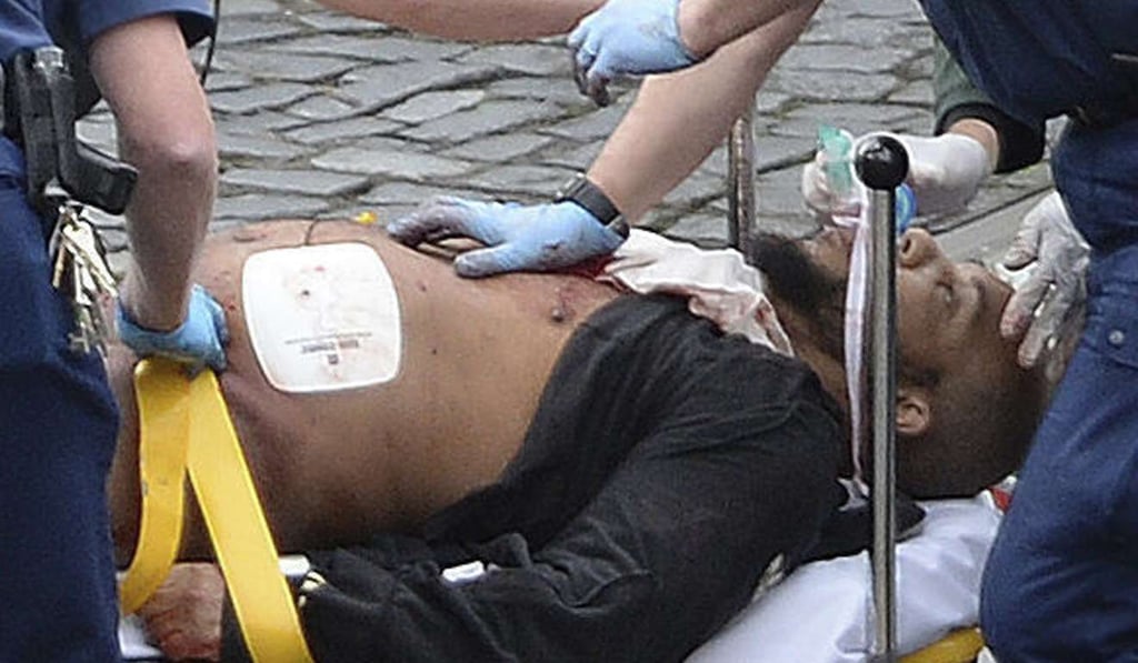 Attacker Khalid Masood is treated by emergency services outside the Houses of Parliament London. He later died of gunshot wounds. Photo: AP