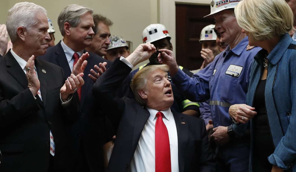 President Donald Trump is surrounded by coal miners and members of congress at a White House event last month. Photo: AP