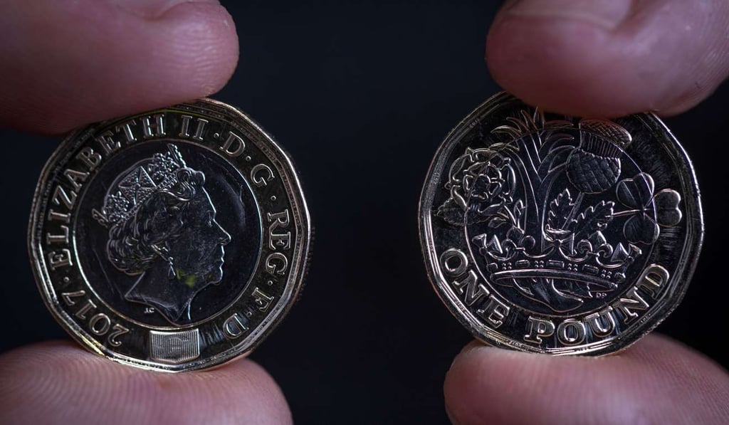 A worker examines new British one pound coins. Photo: Bloomberg