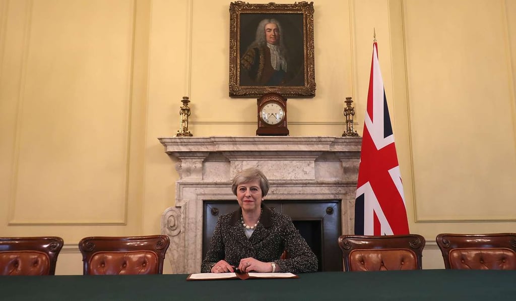 Britain’s Prime Minister Theresa May, below a painting of Britain’s first Prime Minister Robert Walpole, signs the official letter to European Council President Donald Tusk, invoking Article 50 and signalling Britain’s intent to leave the EU. Photo: AFP