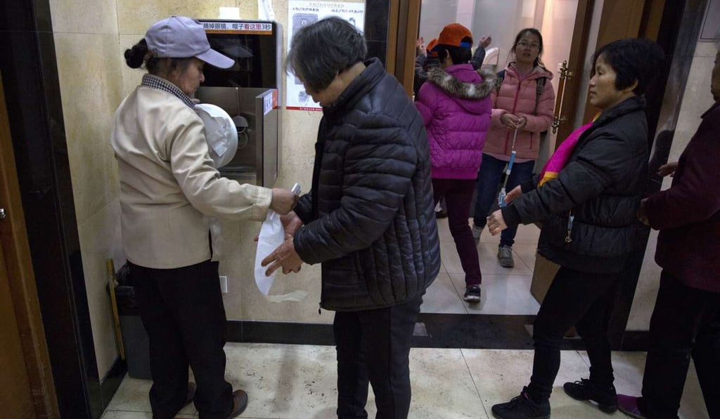 A staff member hands out toilet paper while changing the roll for a facial recognition dispenser at the Temple of Heaven park in Beijing. Photo: AP A staff member hands out toilet paper while changing the roll for a facial recognition dispenser at the Temple of Heaven park in Beijing. Photo: AP