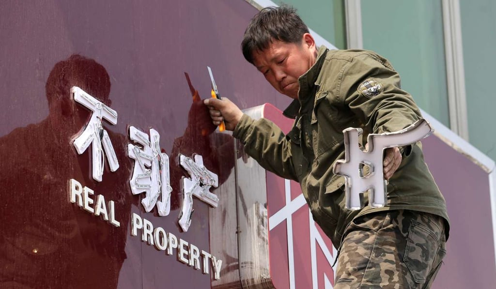 A worker removes the logo of a closed real estate agency. Photo: Reuters