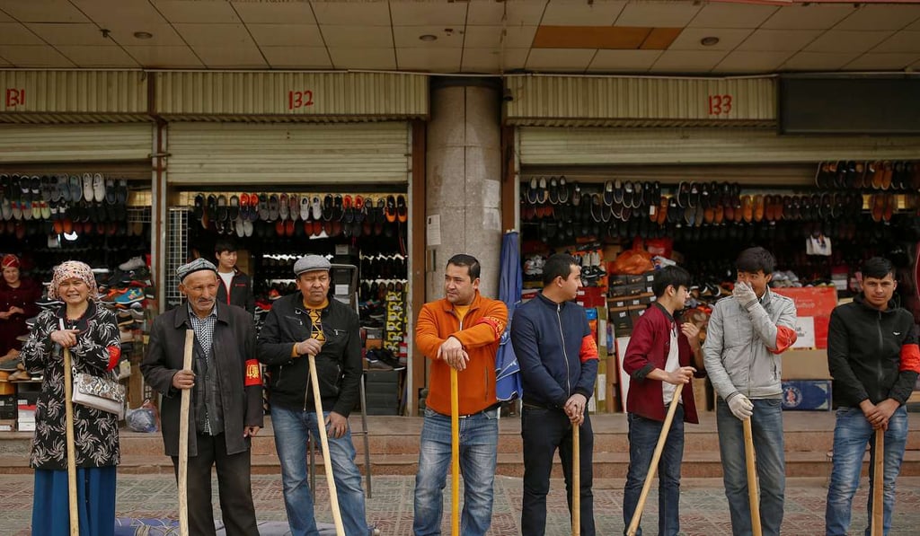 Shopkeepers line up with wooden clubs to perform their daily anti-terror drill outside the bazaar in Kashgar, Xinjiang late last month. Photo: Reuters