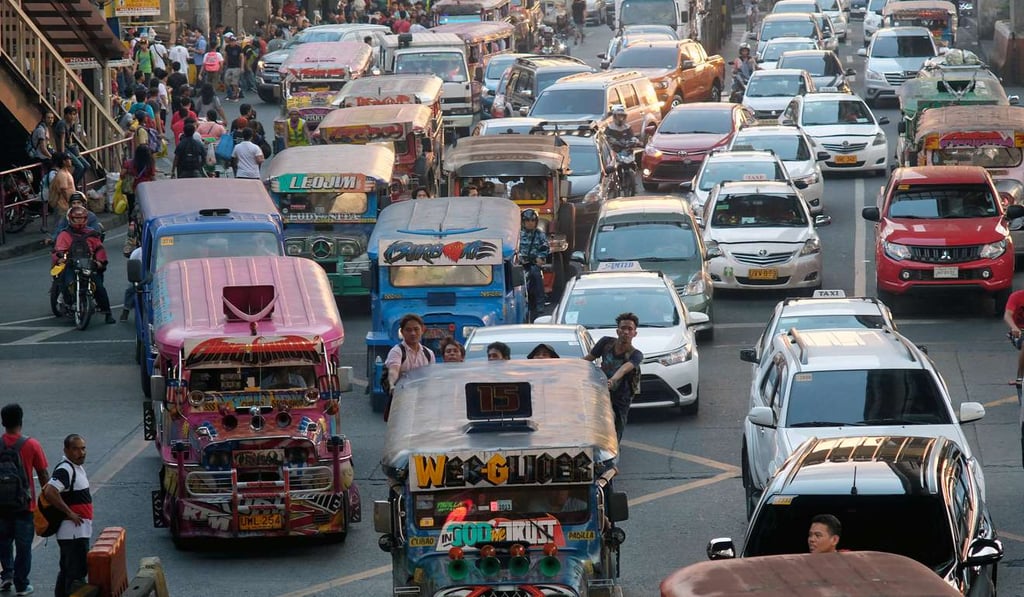 Commuters hang from the back of a jeepney travelling along a road in Manila. Photo: Bloomberg Commuters hang from the back of a jeepney travelling along a road in Manila. Photo: Bloomberg