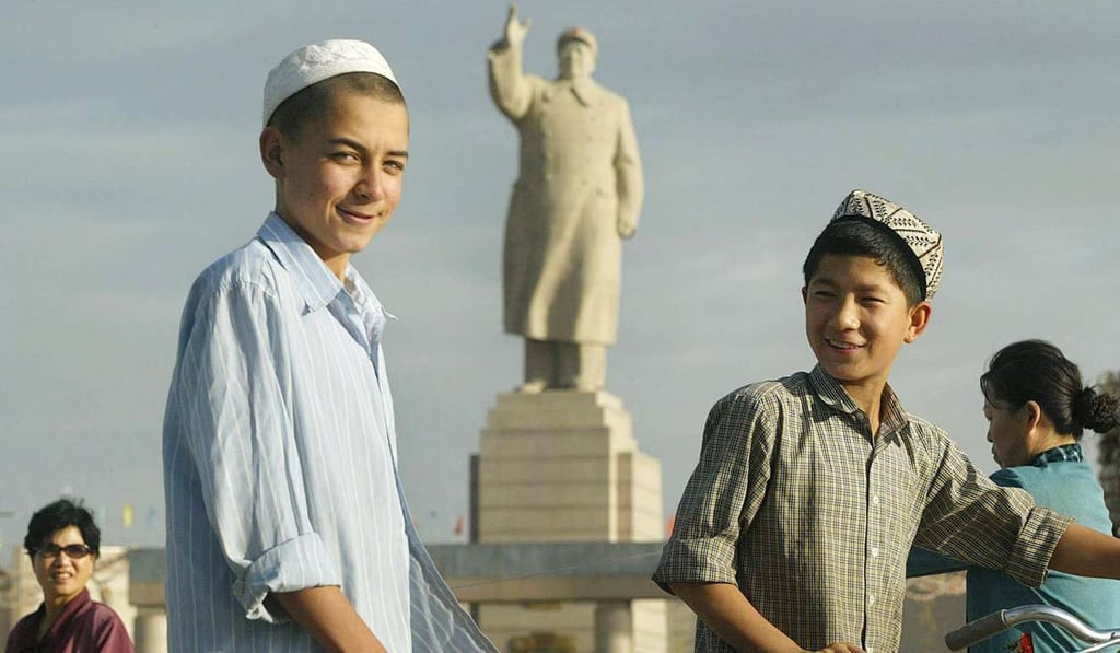 Uygur boys walk past a looming statue of Mao Zedong facing Renmin Square in Kashgar. Picture: AFP