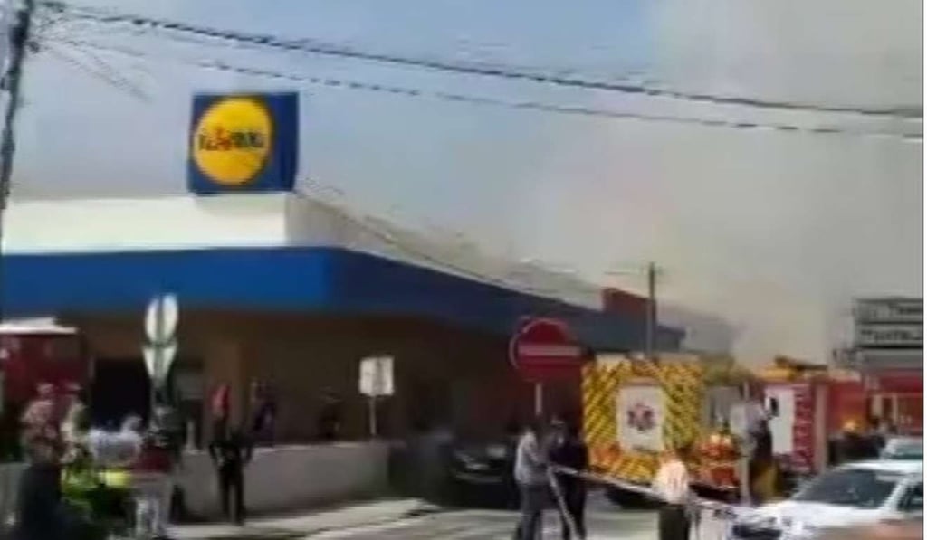 Smoke rises behind a supermarket near Lisbon after a small plane crashed. Photo: AP