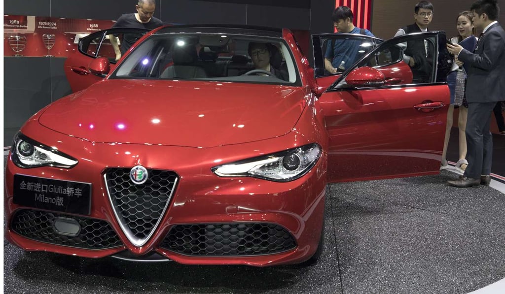 Visitors look at an imported car at the Alfa Romeo stand during the Shanghai Motor Show. Photo: AP