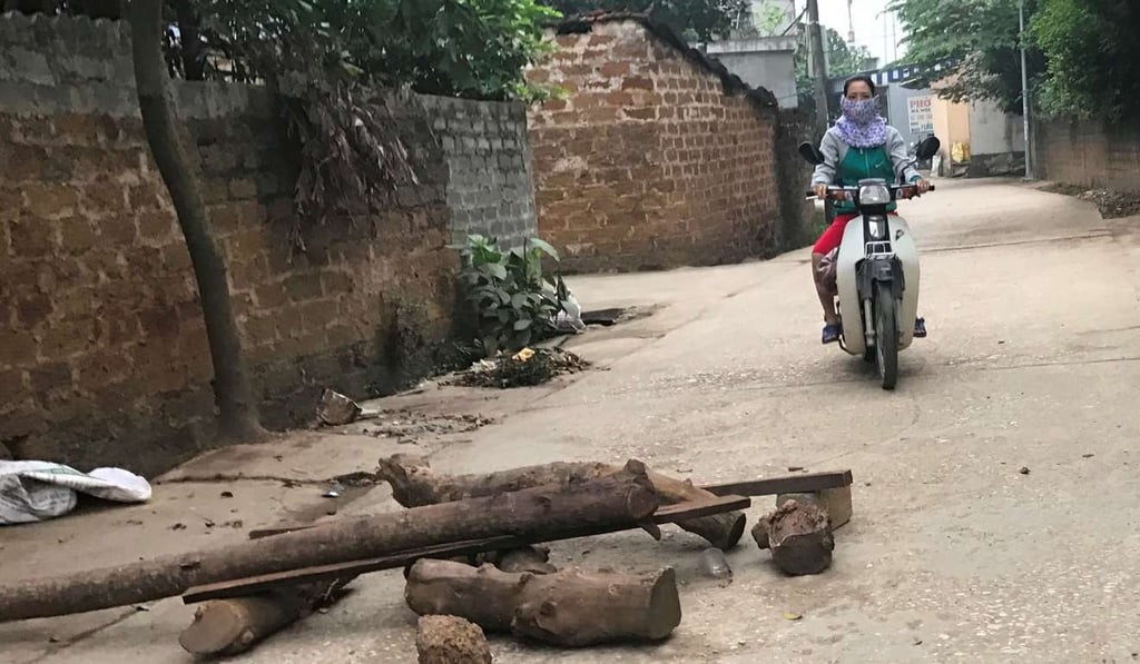 A woman rides a motorcycle on an alley with loose rocks and logs placed by villagers inside the Dong Tam commune in My Duc district on the outskirts of Hanoi, where a hostage stand-off was under way. Photo: AFP A woman rides a motorcycle on an alley with loose rocks and logs placed by villagers inside the Dong Tam commune in My Duc district on the outskirts of Hanoi, where a hostage stand-off was under way. Photo: AFP
