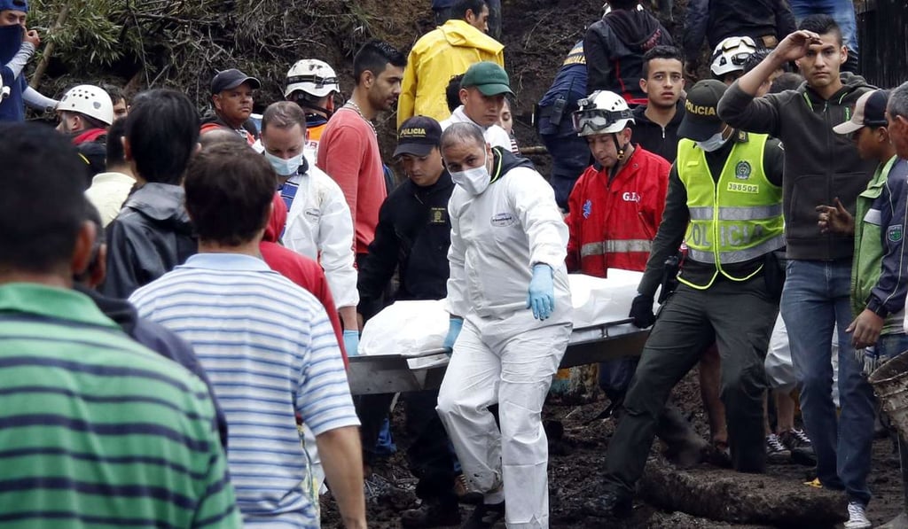 Rescue workers remove the body of a victim where a landslide destroyed several homes in Manizales, Caldas, Colombia. Climate is putting 12 million Colombians at risk of floods and landslides. Photo: EPA Rescue workers remove the body of a victim where a landslide destroyed several homes in Manizales, Caldas, Colombia. Climate is putting 12 million Colombians at risk of floods and landslides. Photo: EPA