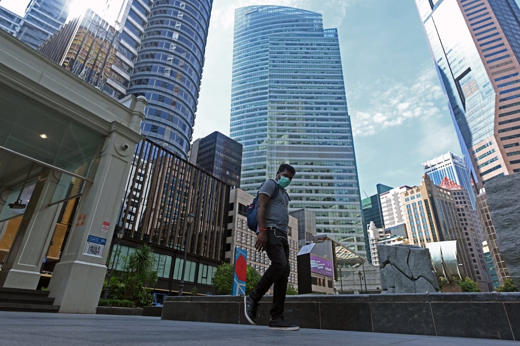 A man wearing a face mask as a preventive measure against the spread of the Covid-19 coronavirus walks next to commercial buildings in the Raffles Place financial business district in Singapore in April 2020. Photo: AFP A man wearing a face mask as a preventive measure against the spread of the Covid-19 coronavirus walks next to commercial buildings in the Raffles Place financial business district in Singapore in April 2020. Photo: AFP