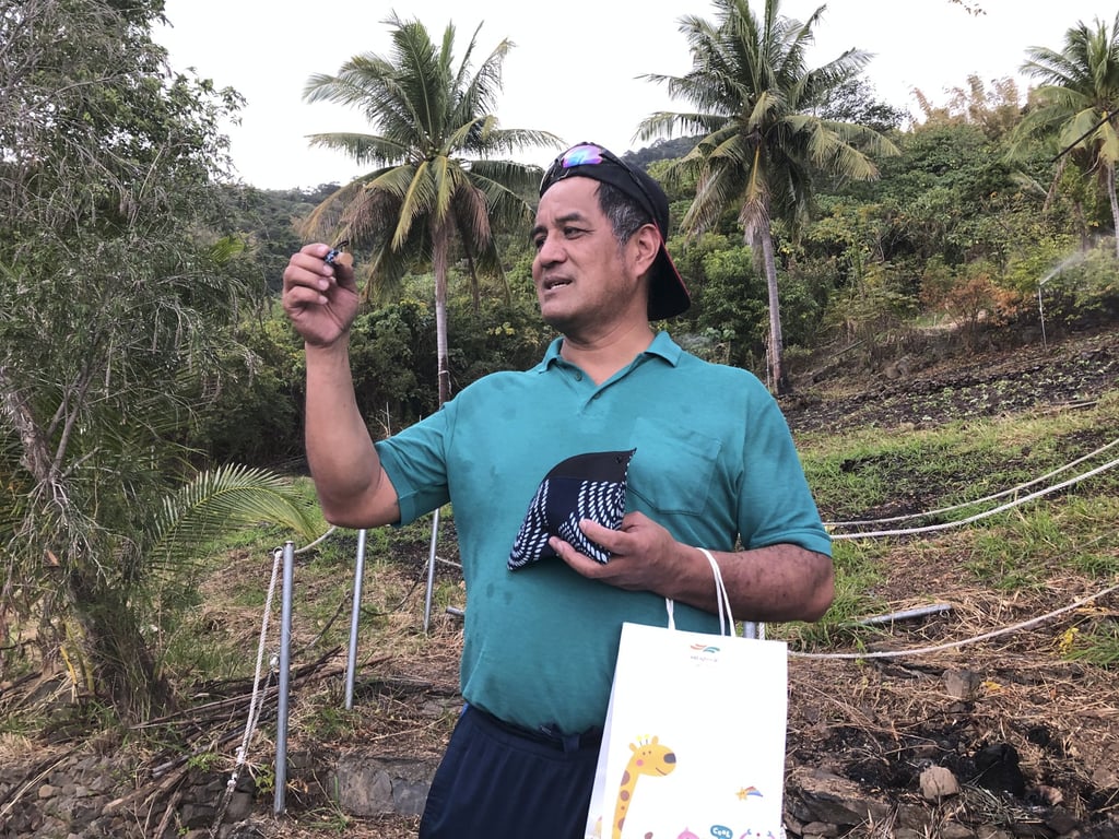 Xianglan Village pastor and landowner Sakinu Tepiq hands out prizes to tourists who helped plant red quinoa on his farm. Photo: Ralph Jennings