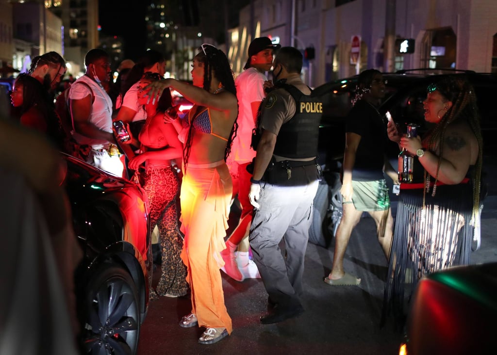 A Miami Dade police officer directs people out of the area as an 8pm curfew goes into effect on Sunday in Miami Beach. Photo: Getty Images/AFP