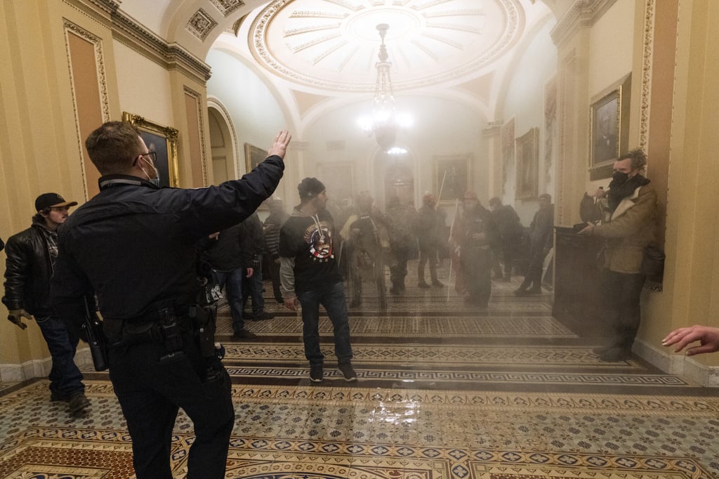 Smoke fills the walkway outside the Senate Chamber as rioters are confronted by US Capitol Police officers on January 6. Photo: AP