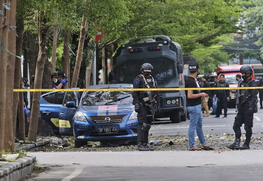 Police officers inspect the site of the explosion outside the church in Makassar on Sunday. Photo: AP