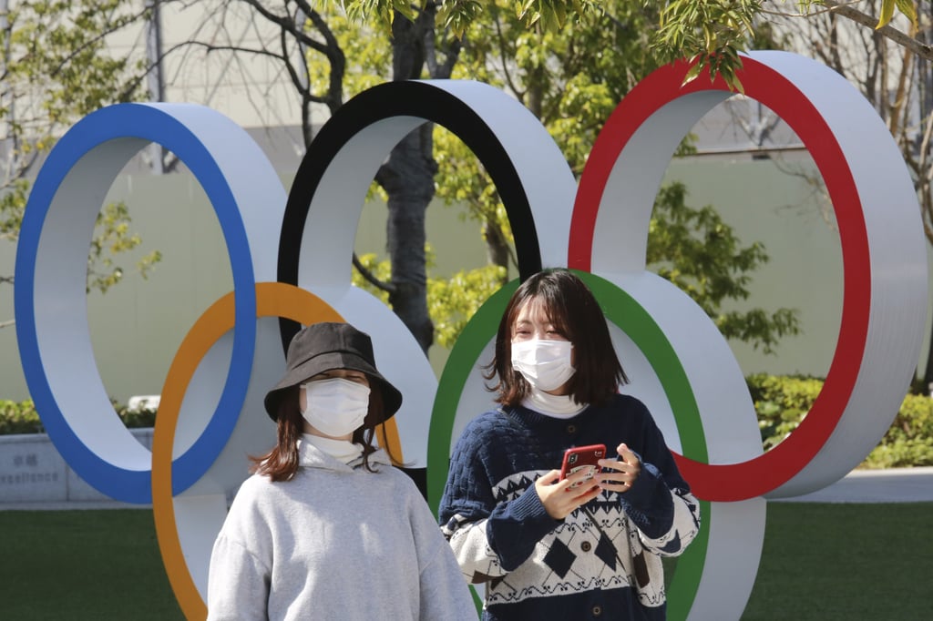 Two people walk past the Olympic rings in Tokyo, Japan as the four-month countdown to the Games begin. Photo: AP