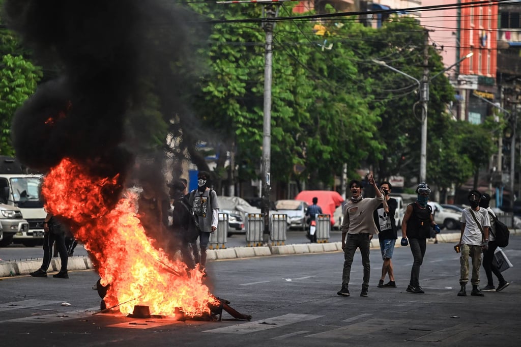 Protesters shout slogans near a burning makeshift barricade along a road during a protest against the military coup, in Yangon on March 30, 2021. Photo: STR/AFP