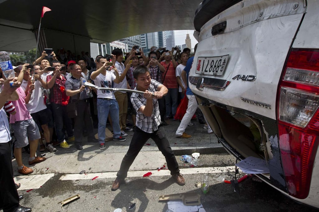 A protester destroys an overturned Japanese-brand police car during a 2012 anti-Japan protest in Shenzhen. Photo: Reuters A protester destroys an overturned Japanese-brand police car during a 2012 anti-Japan protest in Shenzhen. Photo: Reuters