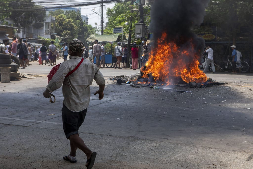 A protester skirts a pile of burning tires during a demonstration against the junta in Yangon. Photo: Zuma Press/TNS A protester skirts a pile of burning tires during a demonstration against the junta in Yangon. Photo: Zuma Press/TNS