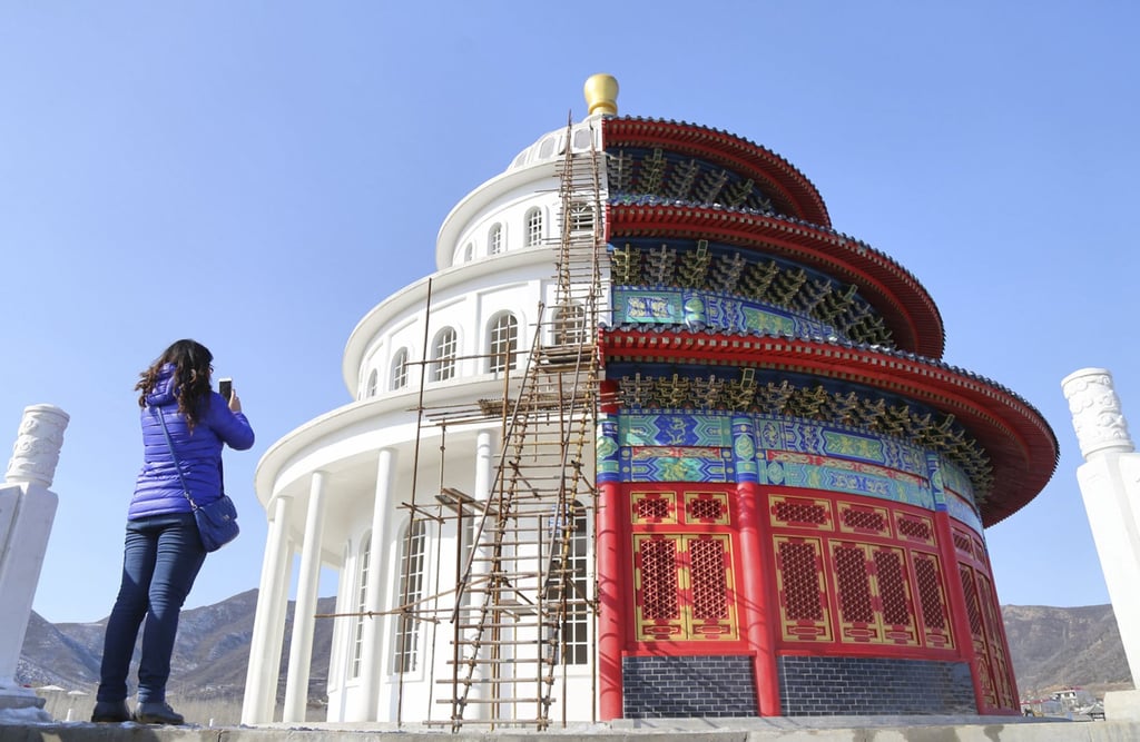 A woman takes pictures of a building that is half of a replica of the Qinian Hall of the Temple of the Heaven (R) and half of a western building. Photo: Reuters