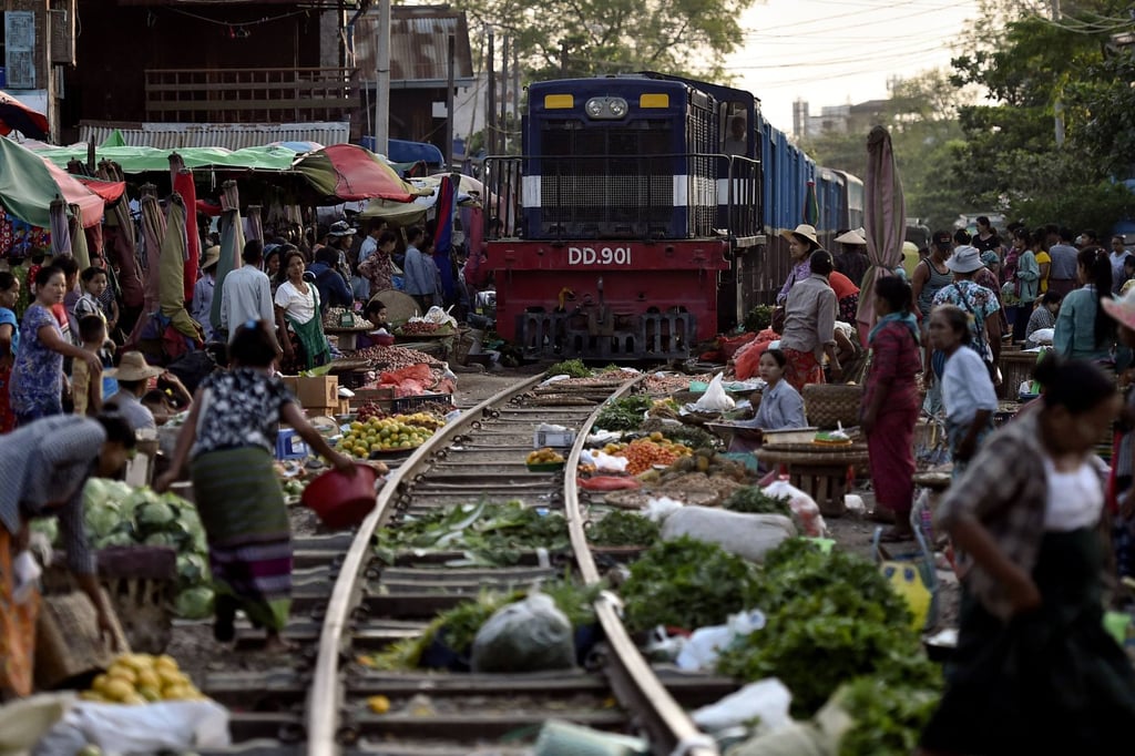 Bazaar vendors move their products as a train approaches in Mandalay. File photo: AFP