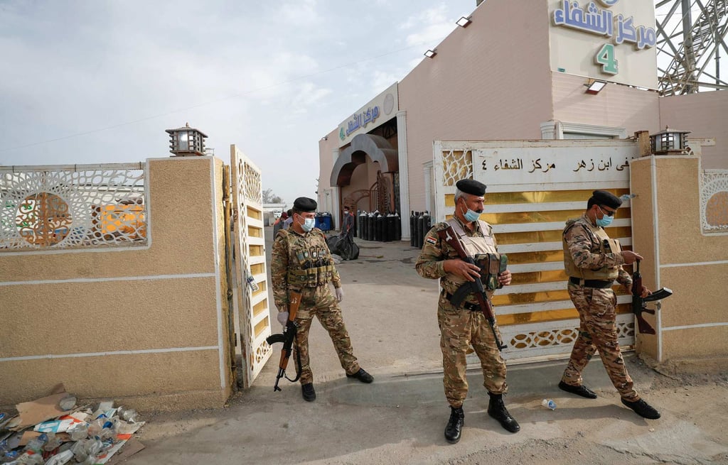 Iraqi policemen stand at the gate of Ibn Al-Khatib Hospital in Baghdad after a fire erupted in the medical facility reserved for the most severe Covid-19 cases. Photo: AFP