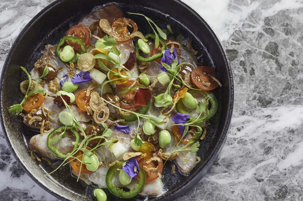 Hamachi ceviche with cherry tomato, black garlic edamame and aromatic herbs, topped with fried onions. Photo: handout