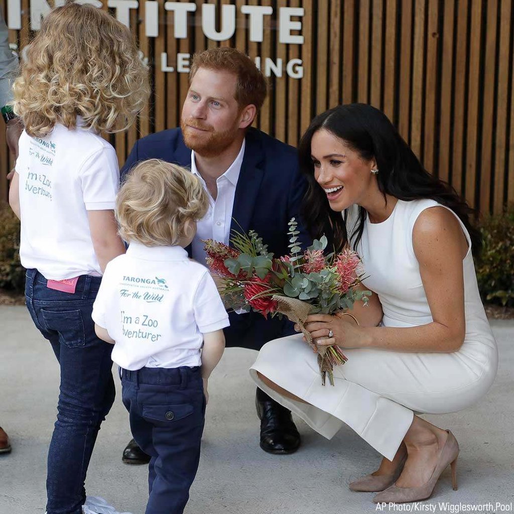 Prince Harry and Meghan Markle, Duchess of Sussex, receive native flowers from Finley Blue and Dasha Gallagher, left, at Taronga Zoo in Sydney, Australia. Photo: AP